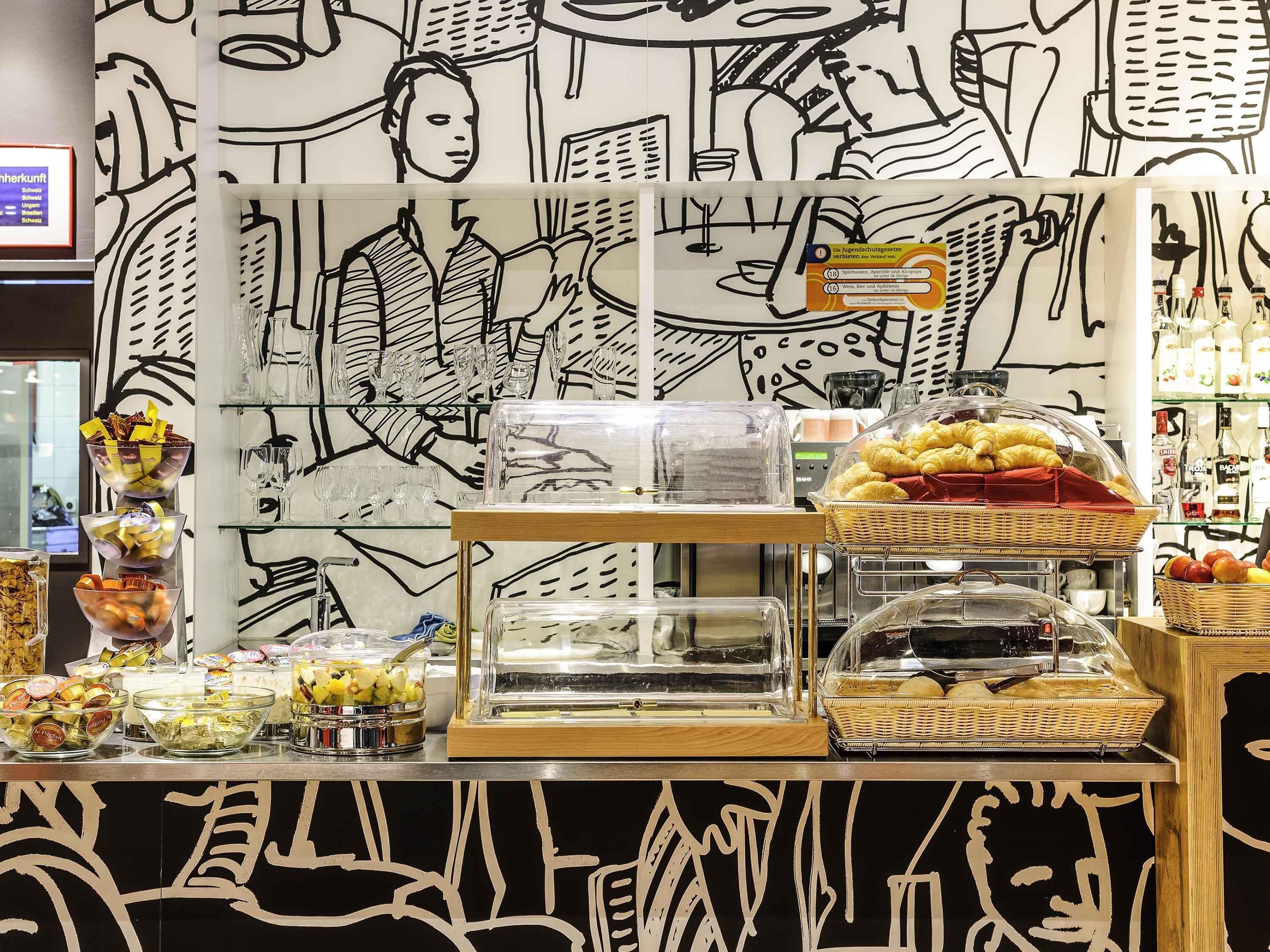 A buffet area with various food items and a wall with a black and white abstract design.