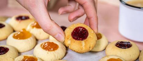 Una mano recogiendo una galleta con relleno de mermelada.