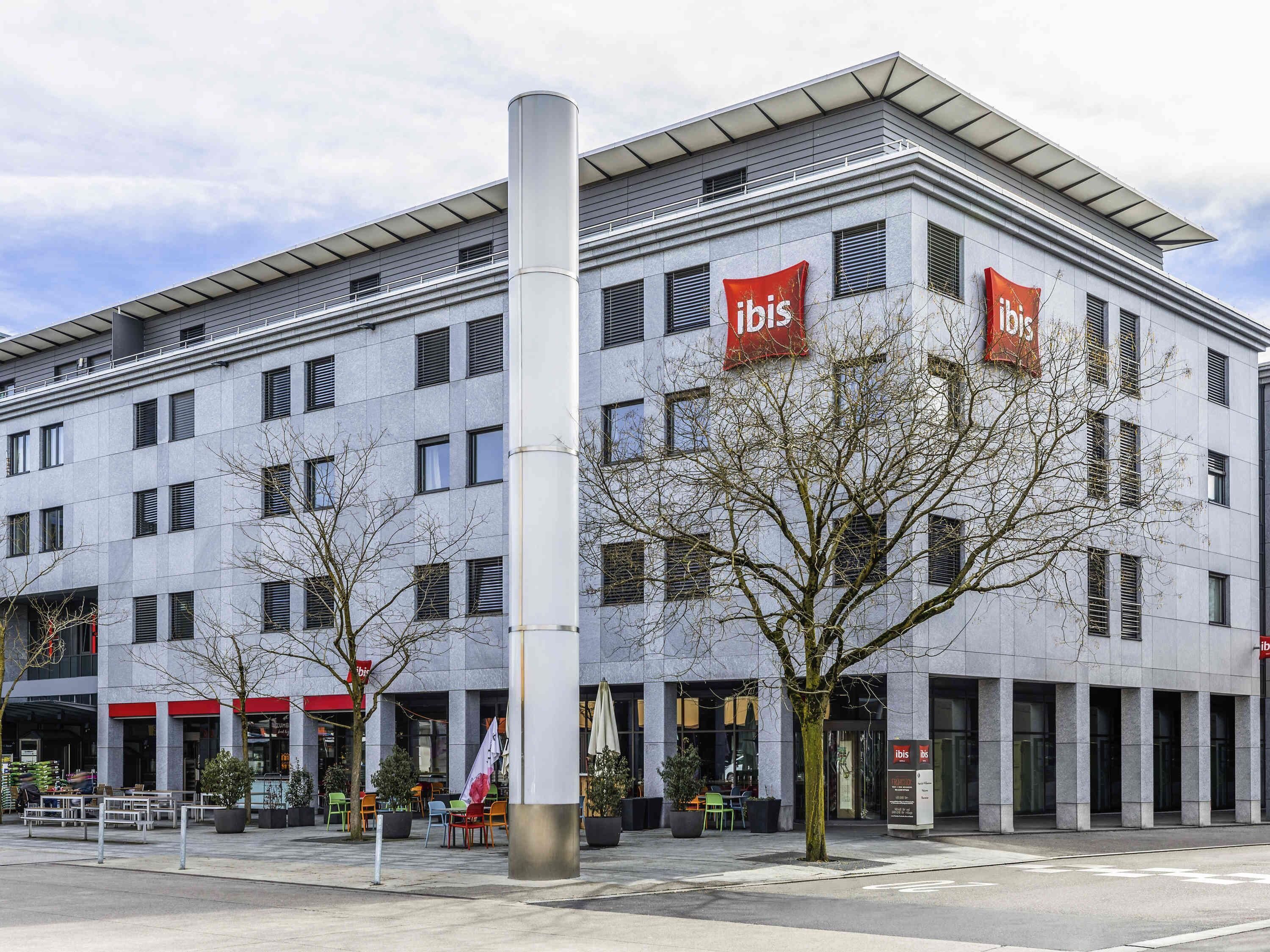 Un bâtiment moderne orné de plusieurs enseignes « ibis », ce qui indique qu’il s’agit d’un hôtel ibis.