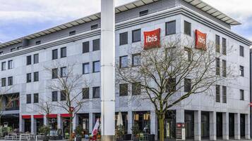 Un bâtiment moderne orné de plusieurs enseignes « ibis », ce qui indique qu’il s’agit d’un hôtel ibis.
