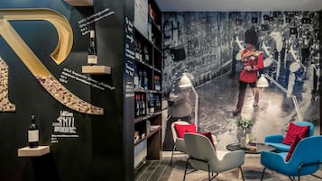 A modern interior with a large 'R' sculpture, wine bottles, and a mural of a guard.