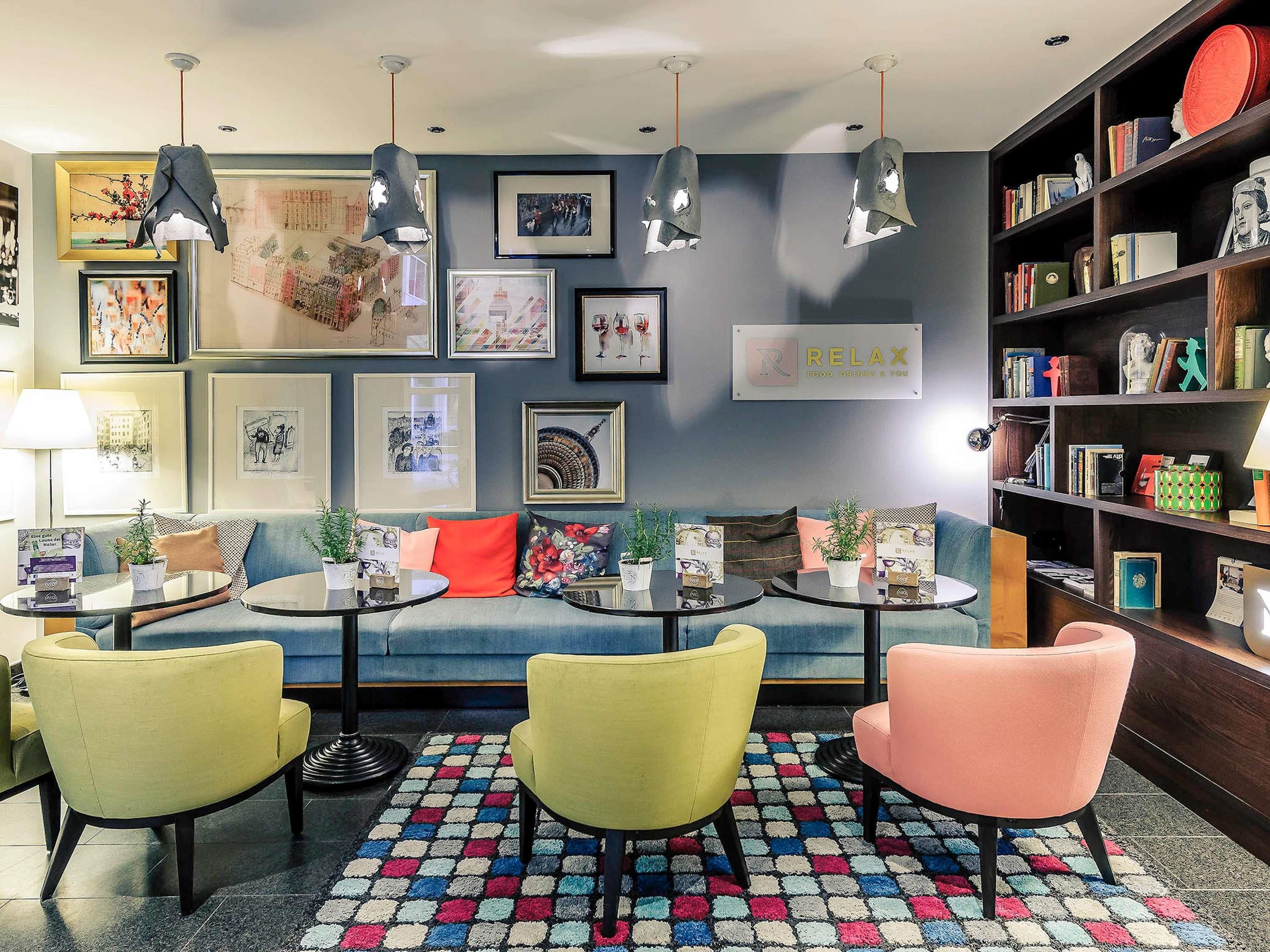 A cozy lounge area with a sofa, two armchairs, a coffee table, and a bookshelf filled with books and decorative items.