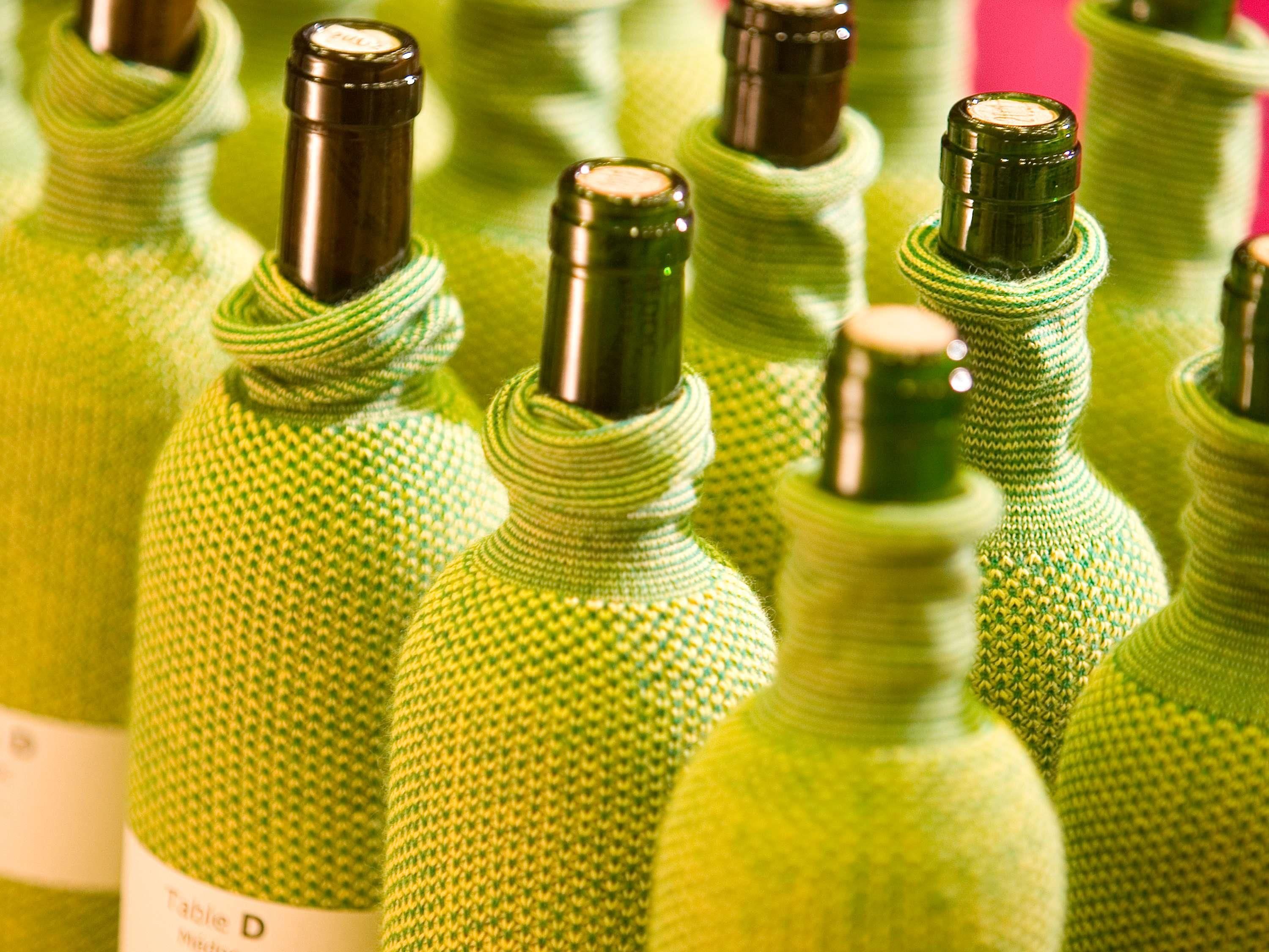 A collection of green wine bottles with labels, arranged closely together.