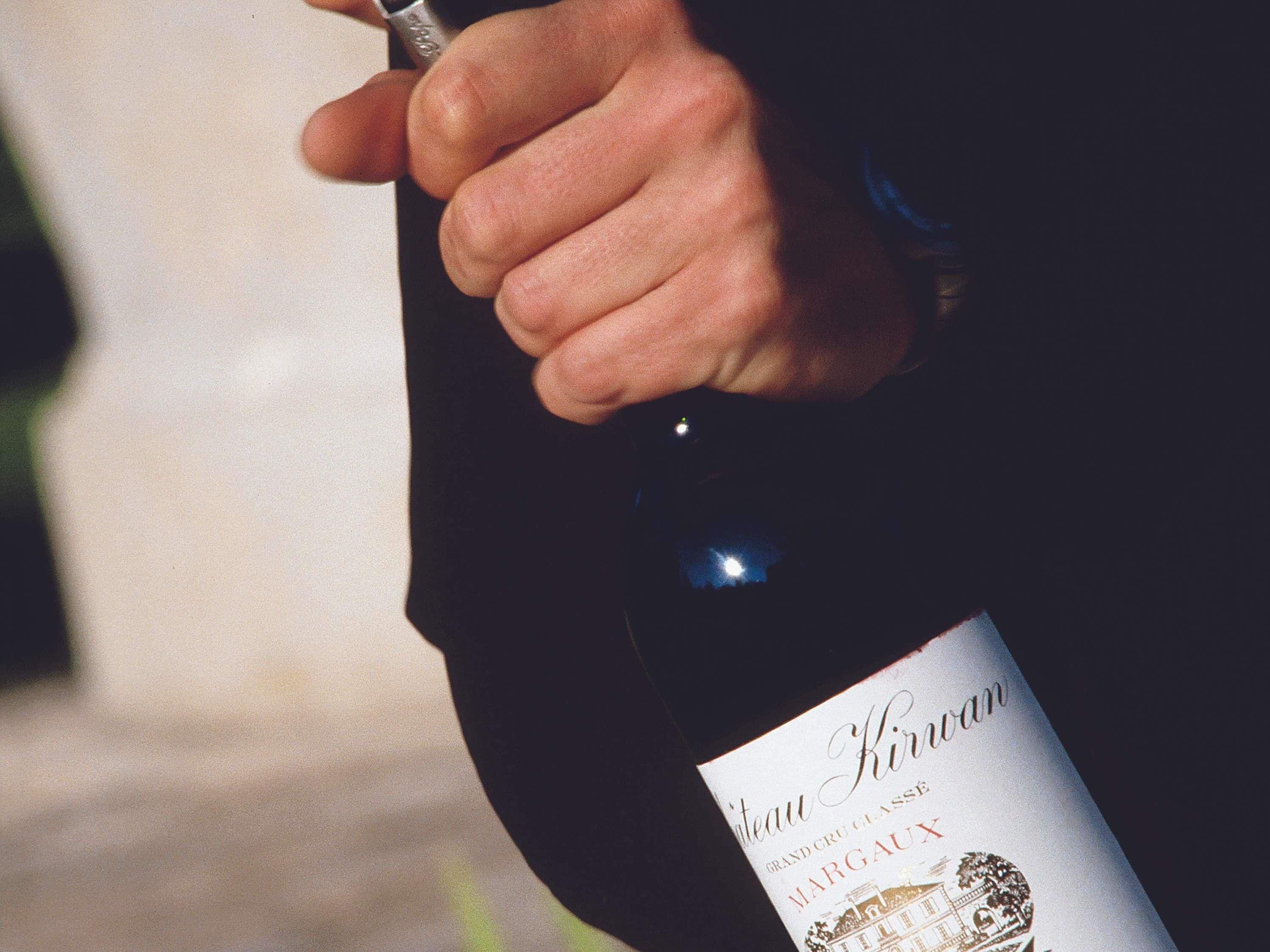 A hand holding a bottle of wine with a label that reads 'Chateau Kiryan Grand Cru Classé Margaux.'