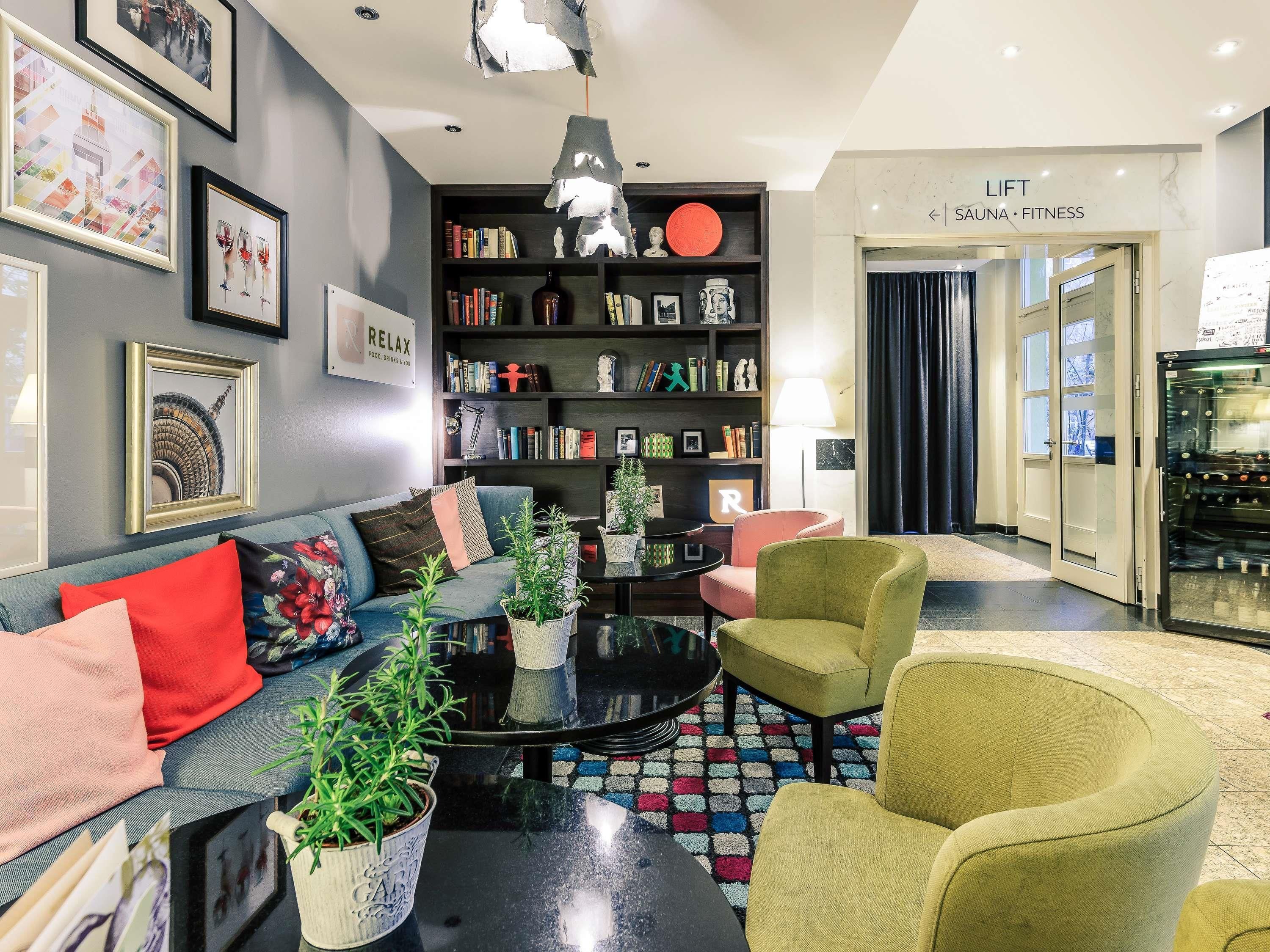 Een moderne woonkamer met een bank, fauteuils, een salontafel en een boekenkast.