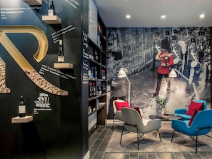 A modern interior with a large 'R' sculpture, wine bottles, and a mural of a guard.