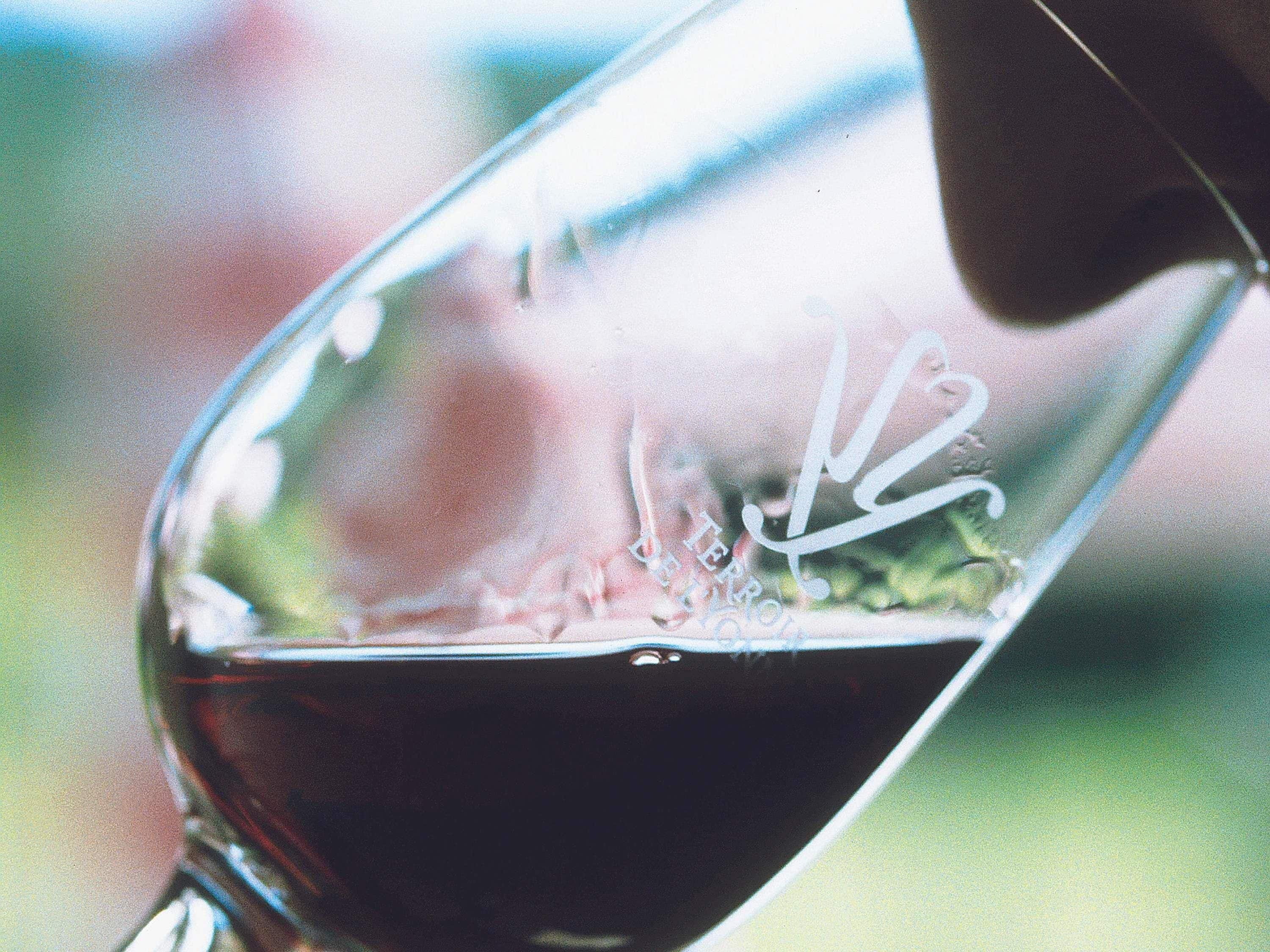 Primer plano de una copa de vino con un líquido oscuro, probablemente vino, siendo servido.