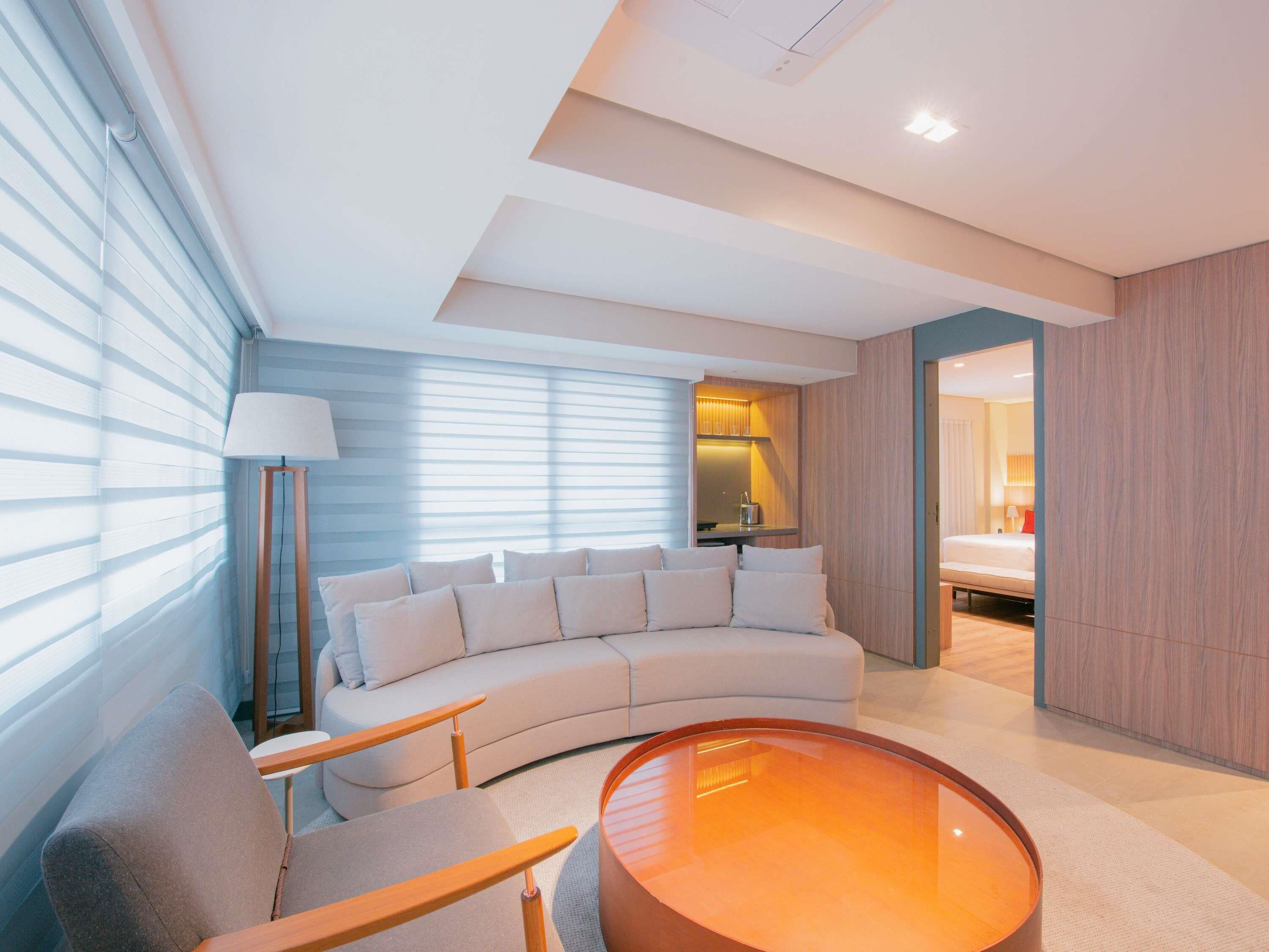 A modern living room with a curved sofa, a round coffee table, and a lamp.