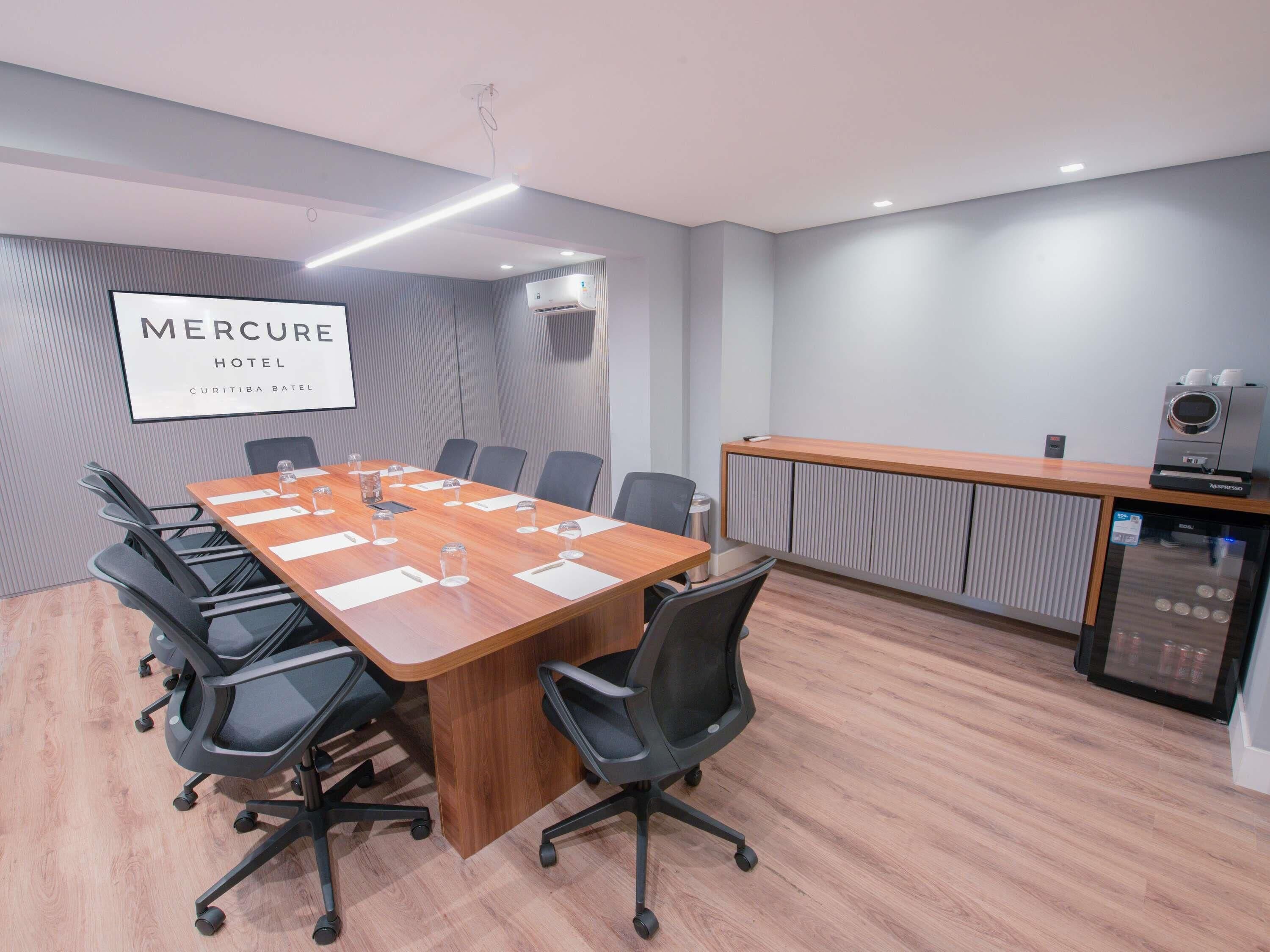 Un salón de conferencias con una larga mesa, sillas, una máquina de café y un equipo de aire acondicionado.