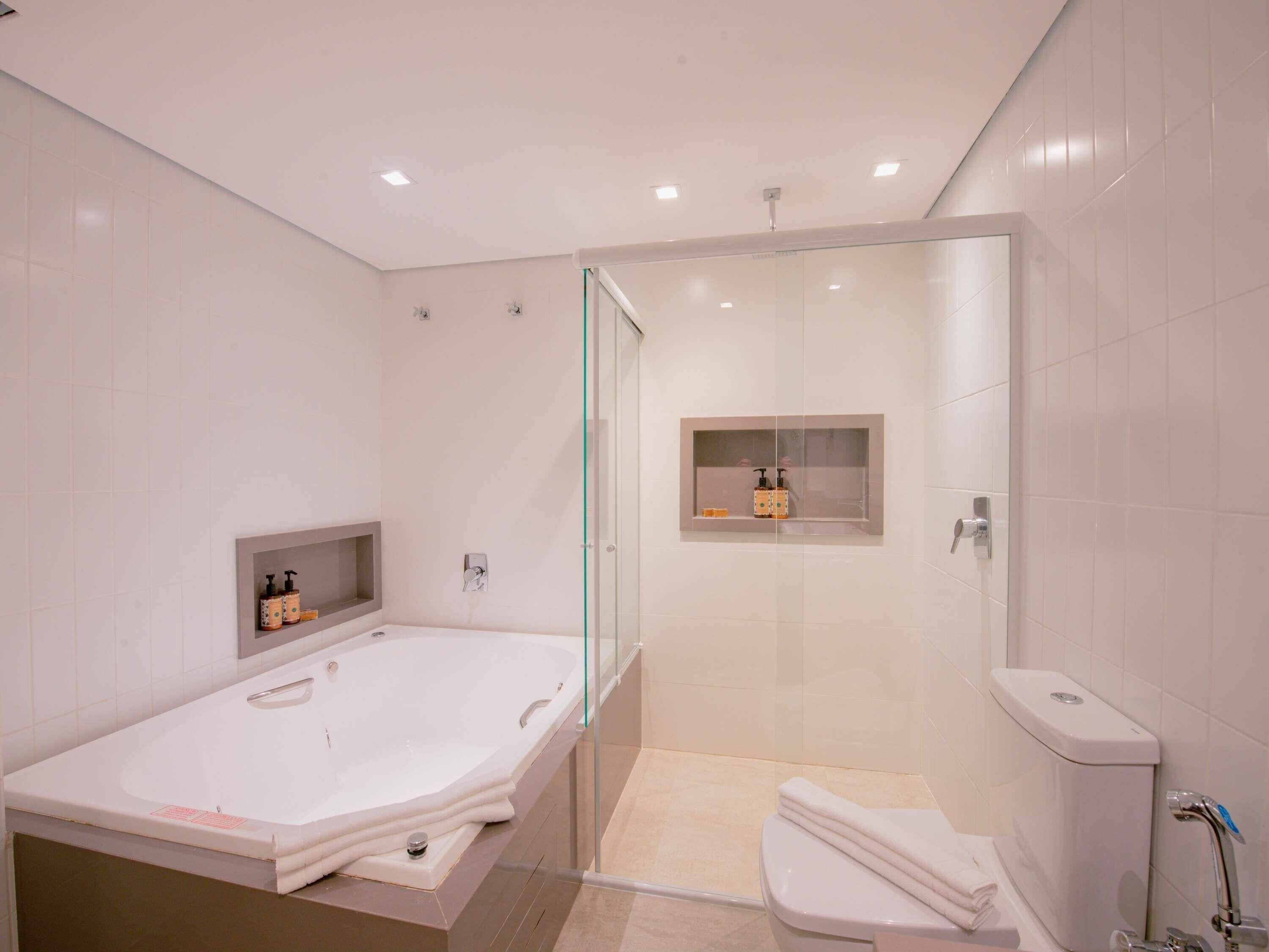 Et moderne badeværelse med et stort badekar, et bruseområde med glasvægge og et toilet.