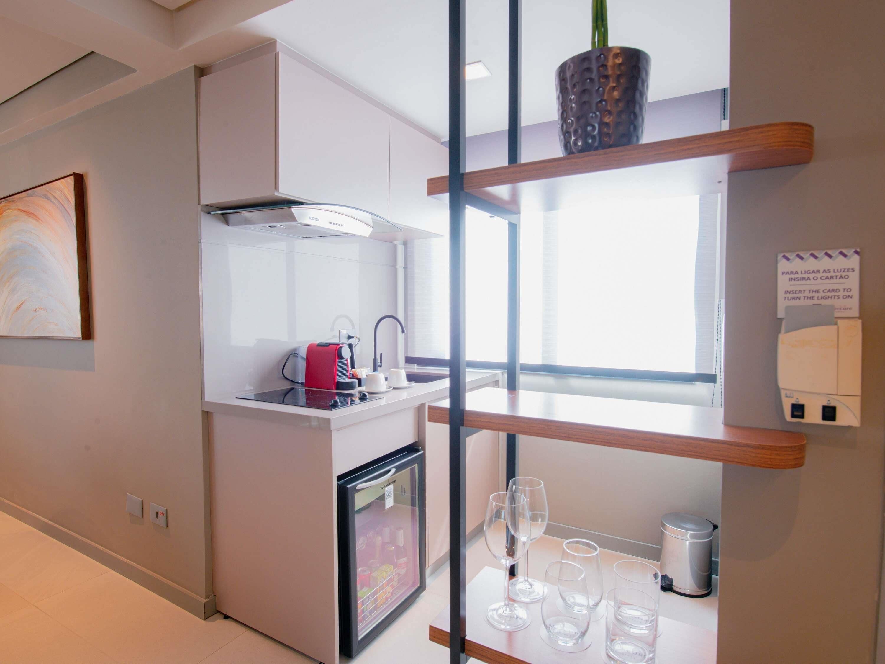 A modern kitchen with a built-in oven, a coffee machine, and wine glasses on a counter.