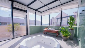 Una piscina interior moderna con hidromasaje, ventanas amplias y plantas en macetas.
