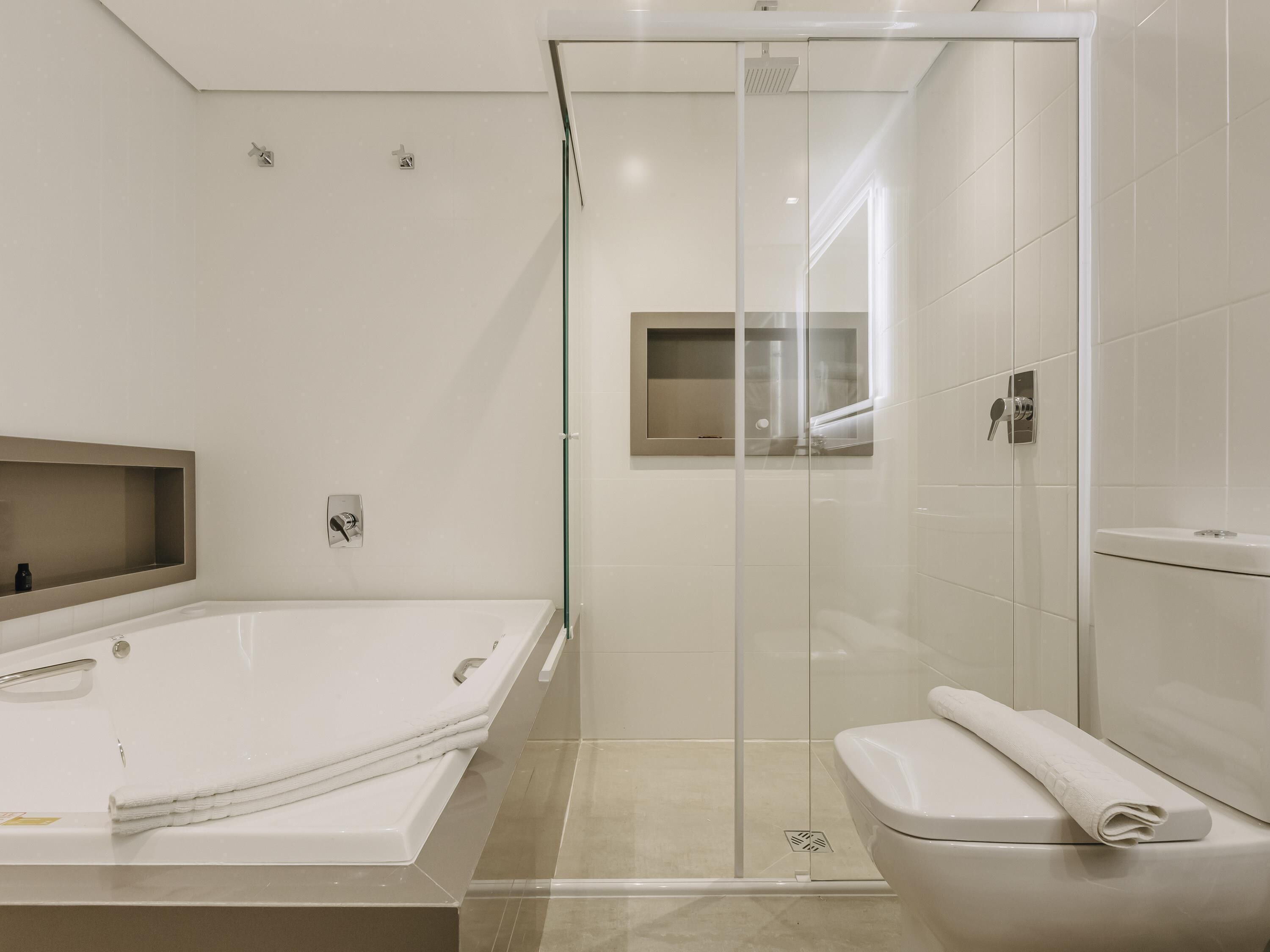A modern bathroom with a glass-enclosed shower, a white bathtub, and a toilet.