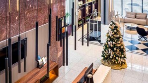 Un hall con mostrador de recepción, un árbol de Navidad, un sofá y una estantería.