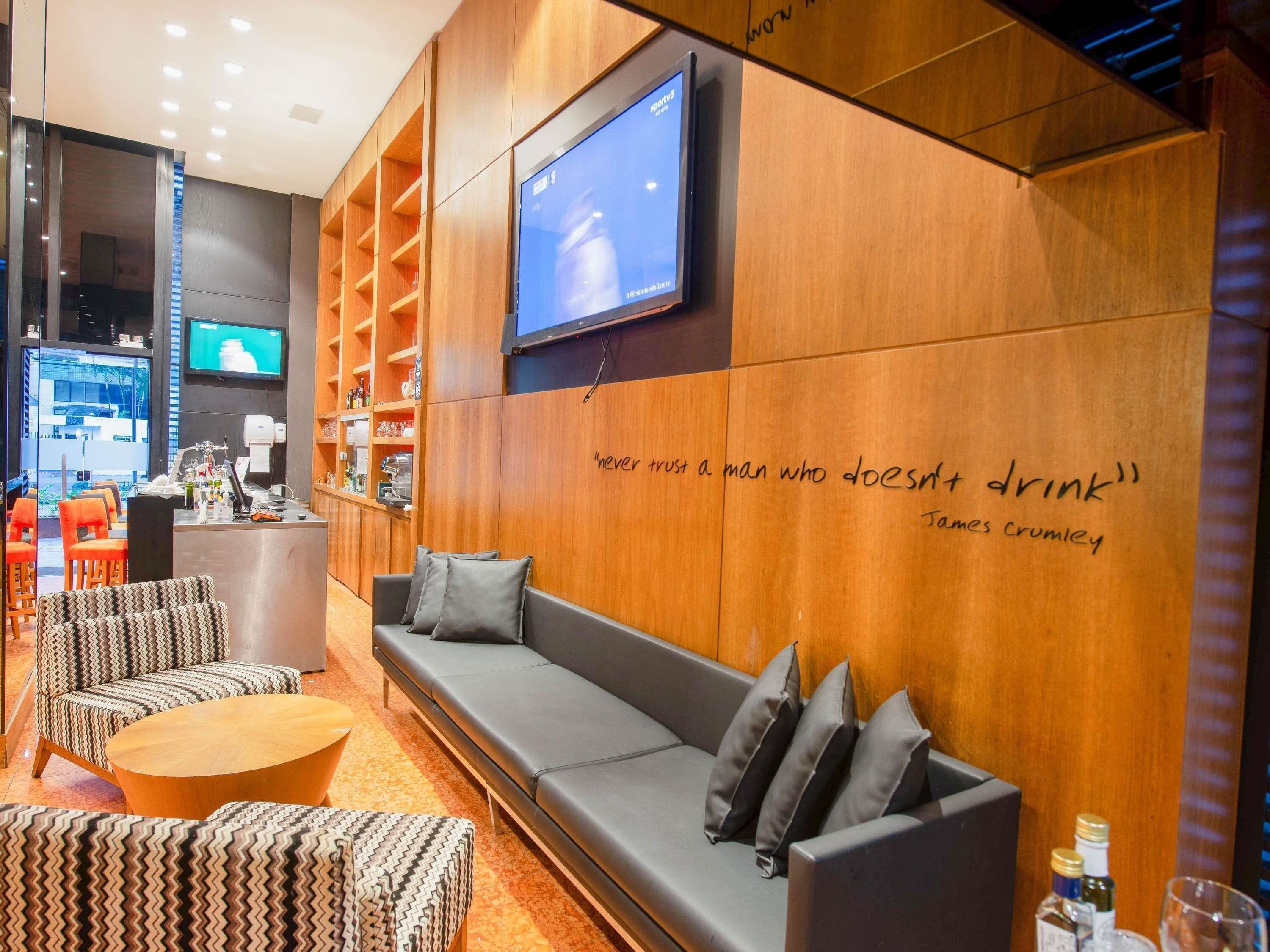 A modern lounge area with a sofa, chairs, a coffee table, and a TV mounted on the wall.