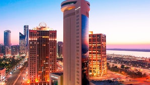 A high-rise hotel with a modern design, featuring a prominent dome on the top and multiple floors with illuminated windows.