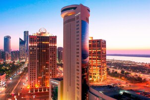 A high-rise hotel with a modern design, featuring a prominent dome on the top and multiple floors with illuminated windows.