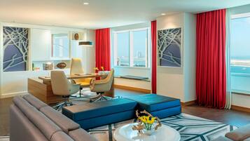 Une chambre d’hôtel moderne dotée d’un coin repas, d’un canapé, d’une table basse et offrant une vue sur le paysage urbain.