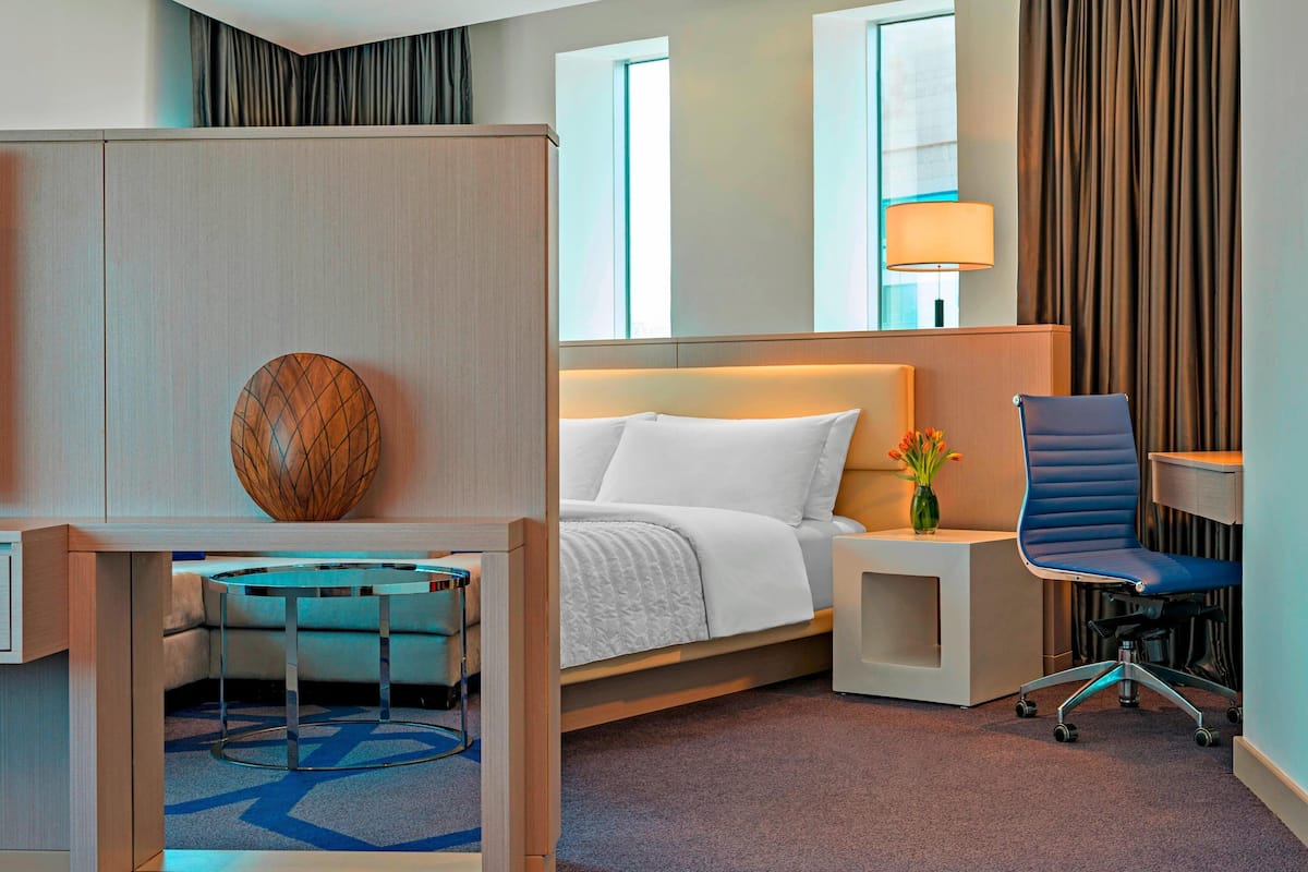 Een hotelkamer met een bed, een bureau, een stoel, een lamp en uitzicht.