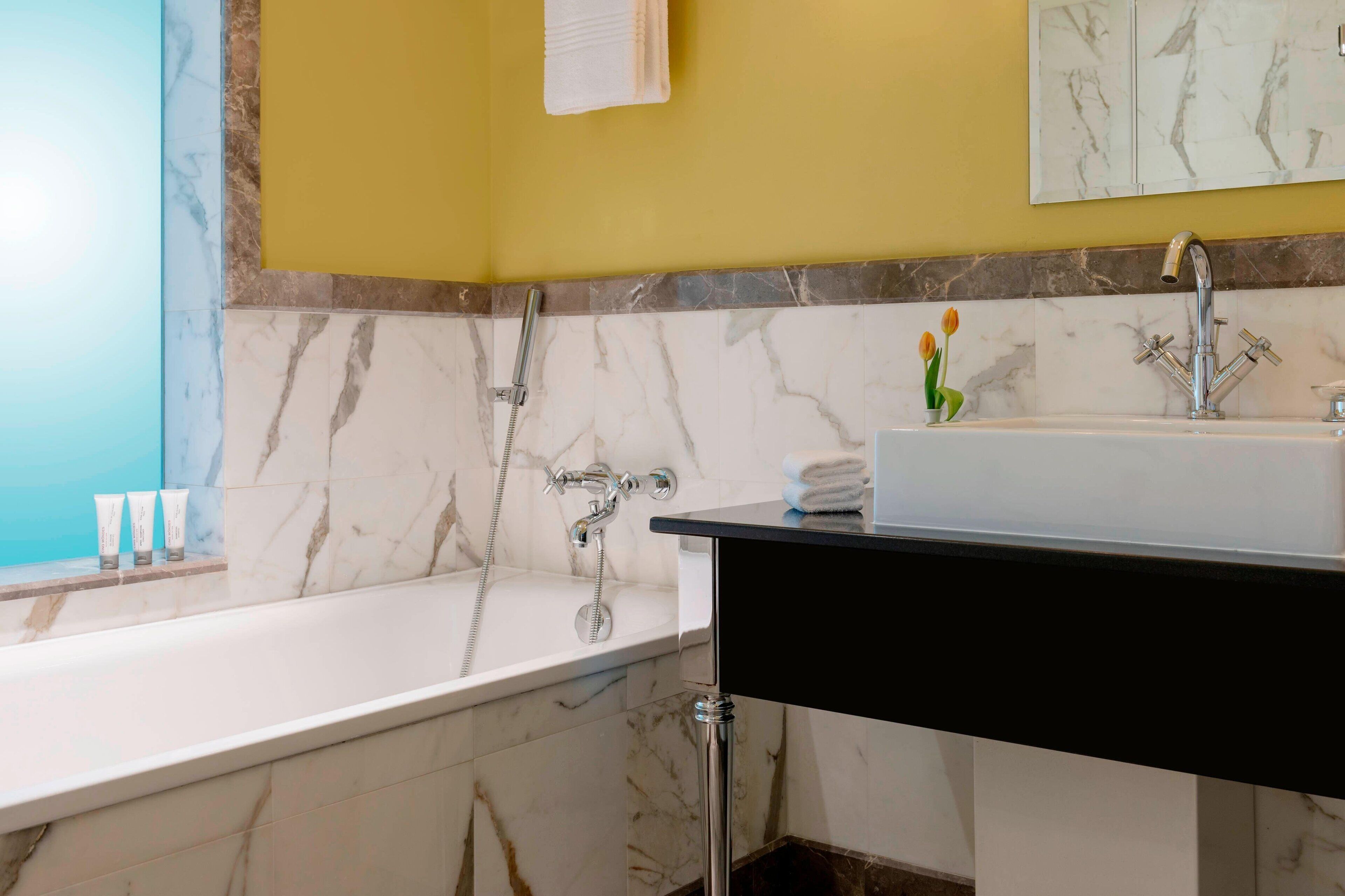 Un baño con bañera, lavamanos y espejo.