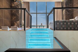A modern interior with a staircase leading to a balcony, marble walls, and a view of the landscape.