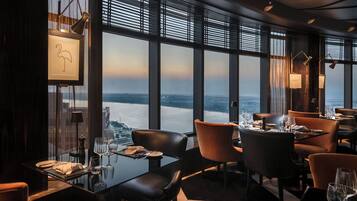 Un restaurante con vistas al agua, grandes ventanales y muebles modernos.