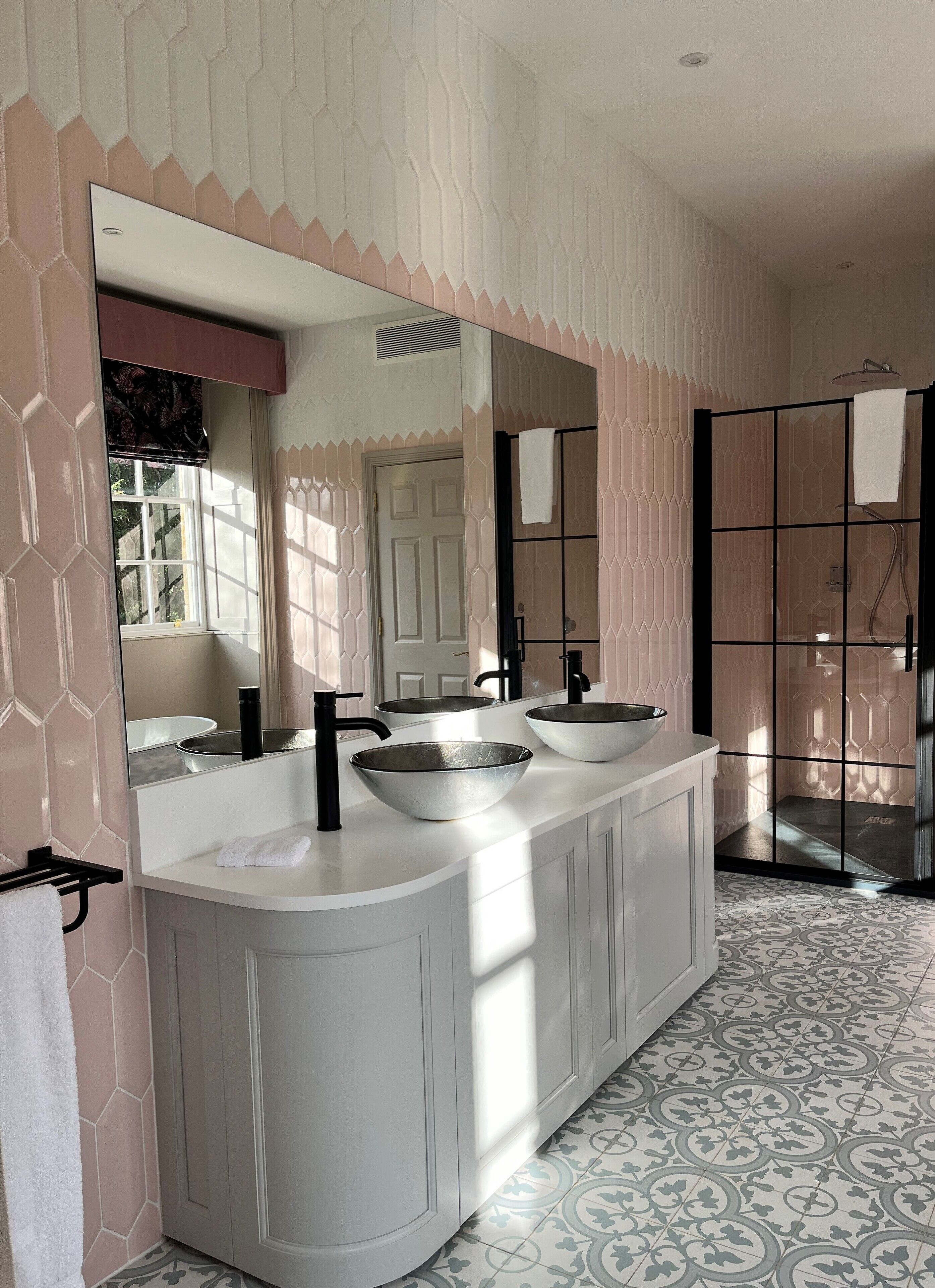 A bathroom with a large mirror, two sinks, and a shower area.
