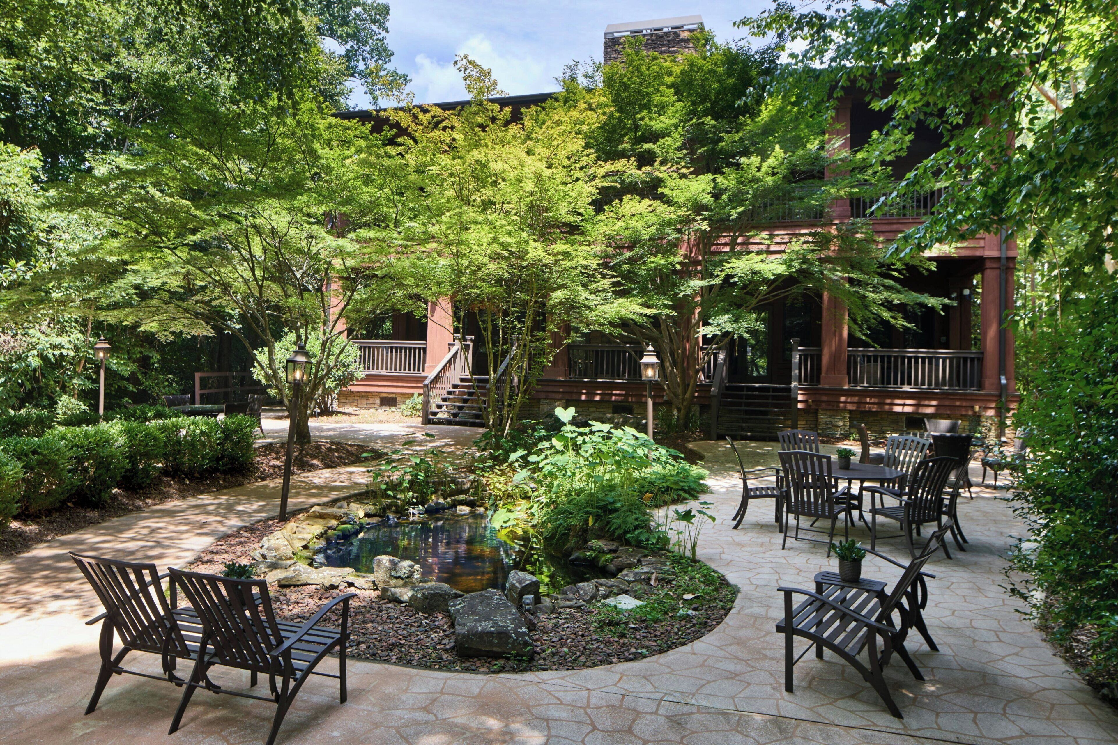 A courtyard with a small pond, surrounded by stone tiles and furnished with outdoor seating.