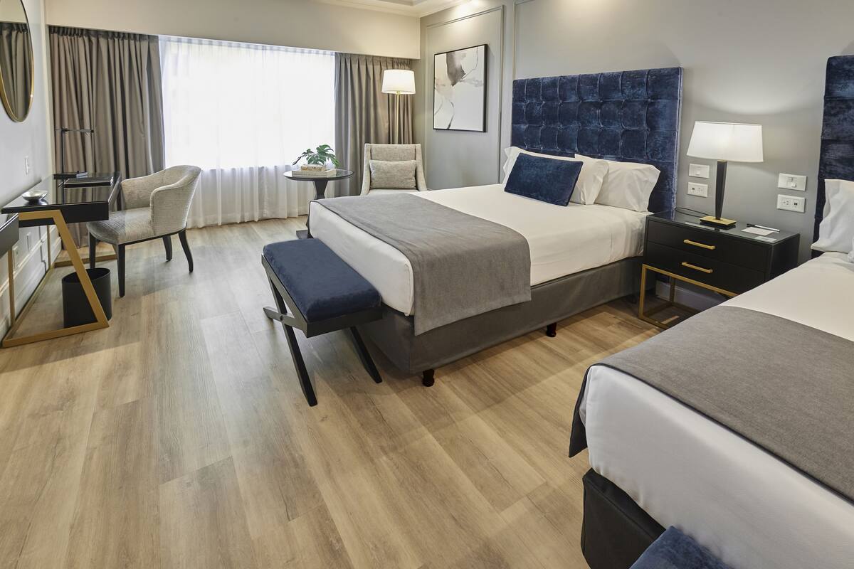 Een hotelkamer met een groot bed, een bureau, een stoel en een tafeltje met een lamp.