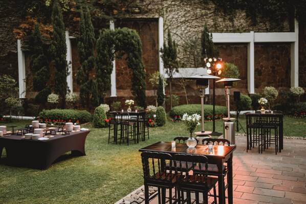 An outdoor patio with tables and chairs, surrounded by greenery and stone walls. - Emperador Hotel Buenos Aires (Buenos Aires)