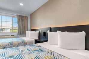 Une chambre d’hôtel avec deux lits, une grande fenêtre avec des rideaux, un téléphone fixé au mur et une table de chevet.