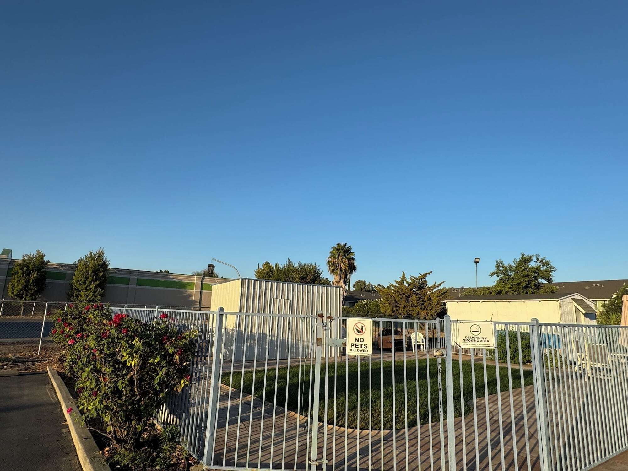 A gated parking area with a 'No Pets Allowed' sign and a 'Smoking Area' sign.