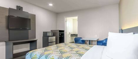A modern hotel room with a bed, a TV, a desk, and a chair.