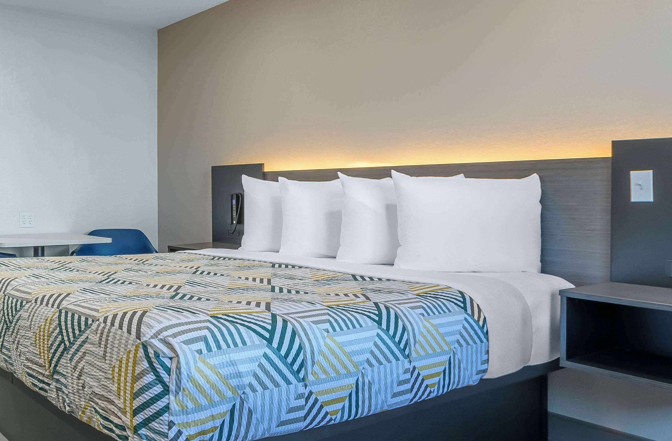 A hotel room with a bed, a desk, and a chair.