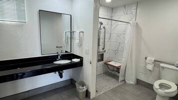 Un baño moderno con un lavamanos negro, inodoro blanco y zona de ducha con mampara de vidrio.