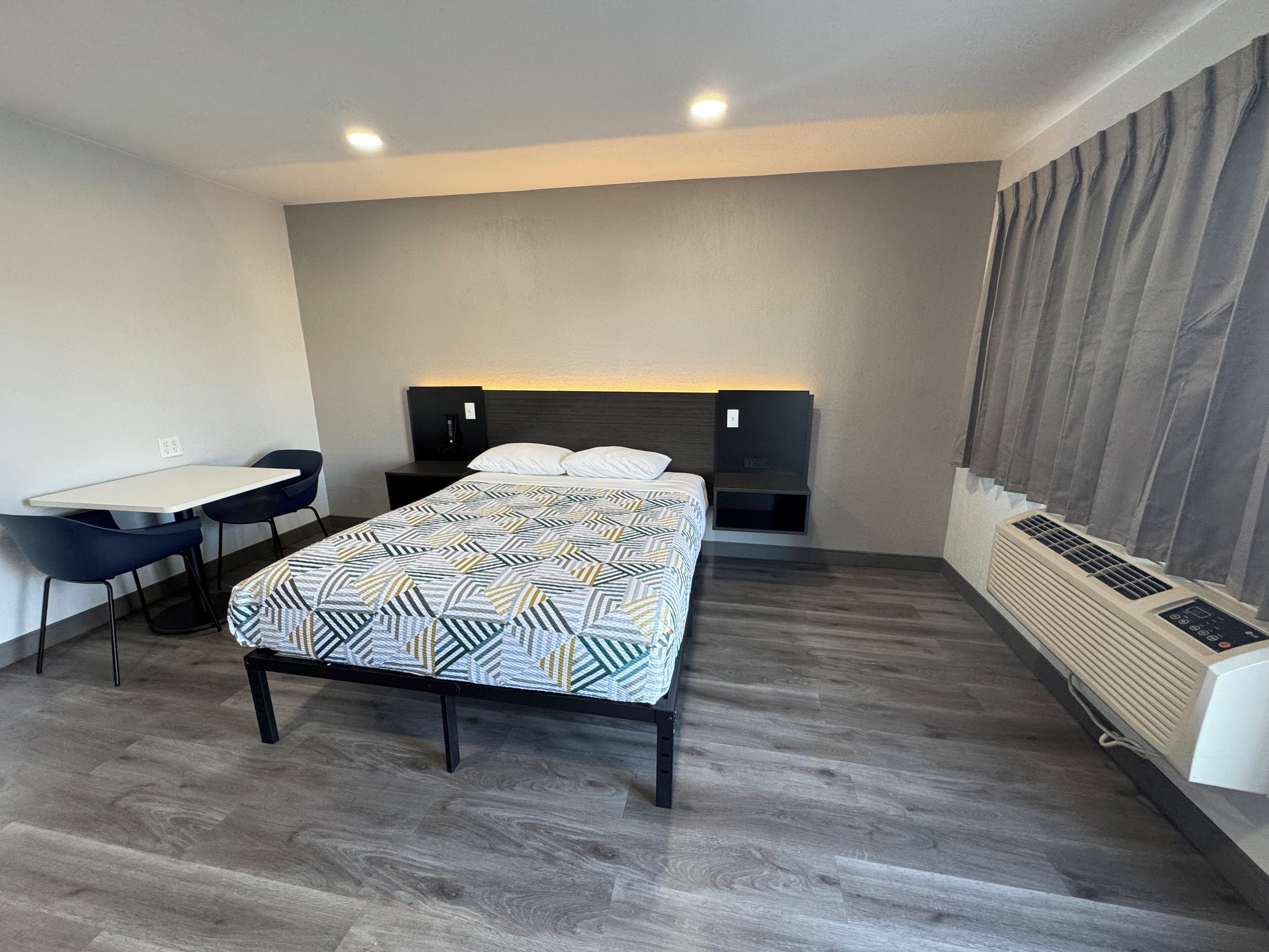 A modern hotel room with a bed, a desk, and a chair.