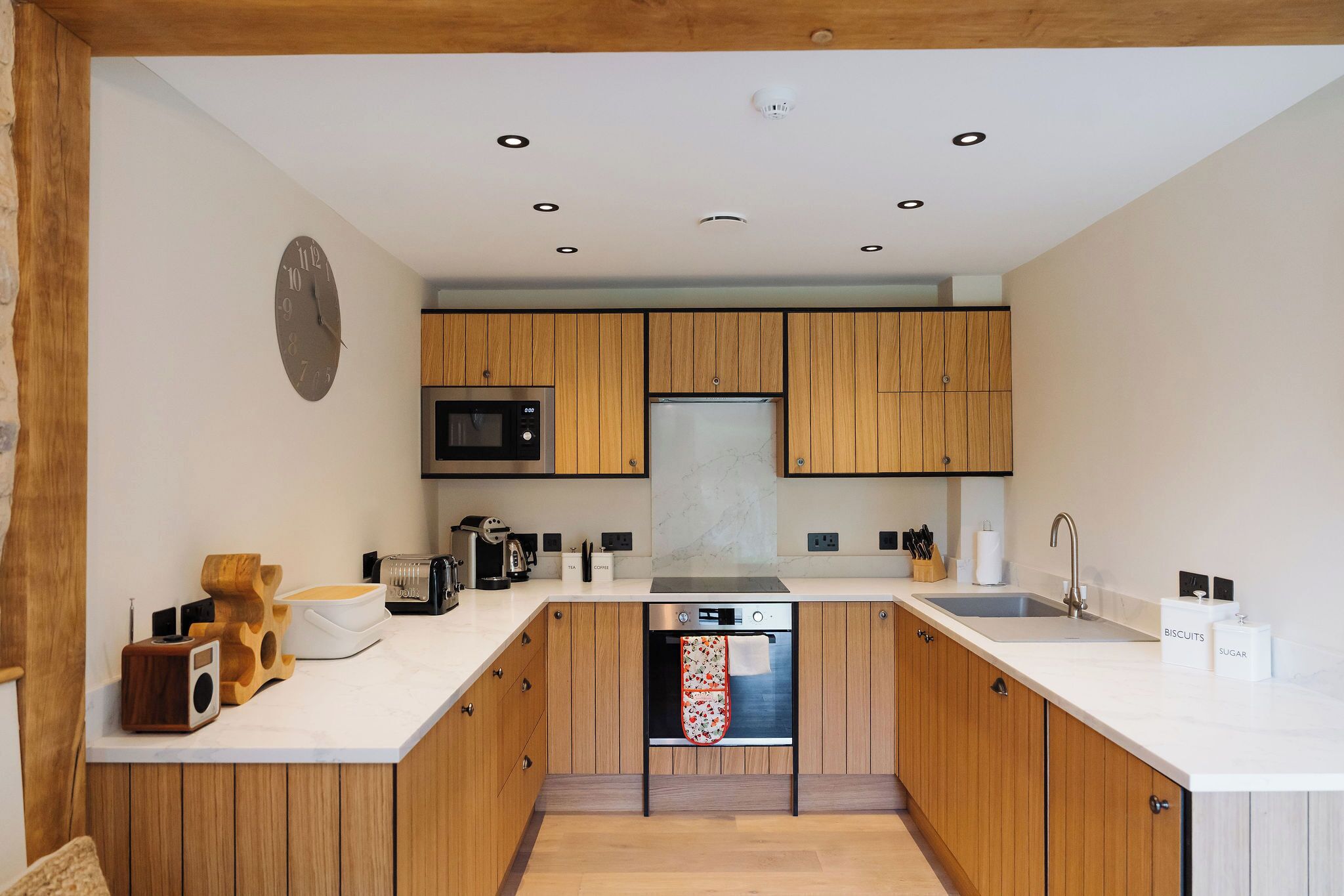 Una cocina moderna con armarios de madera, microondas, refrigerador y horno empotrado.