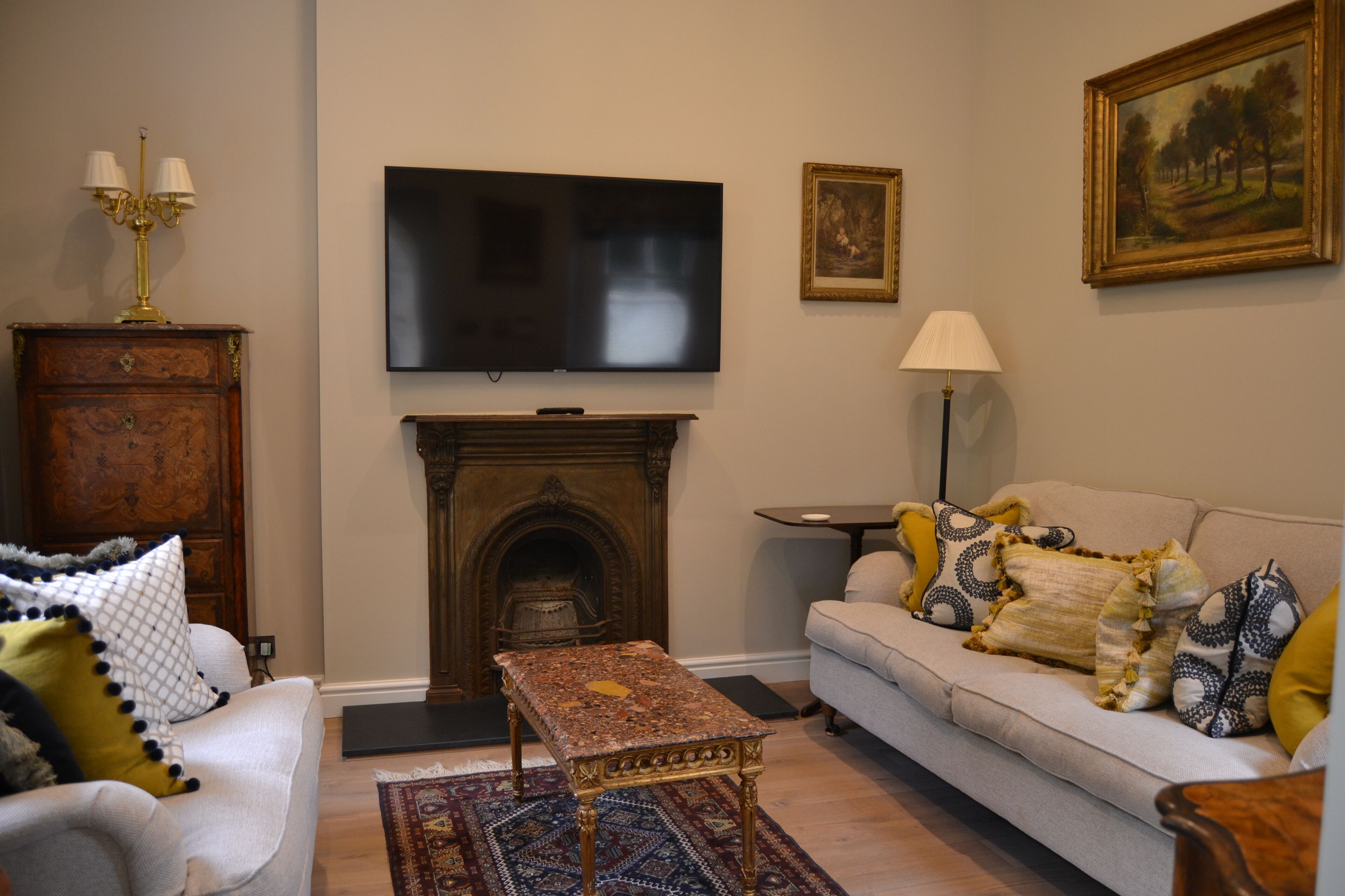 Una sala de estar con chimenea, televisor montado en la pared, sofá con cojines estampados y un mueble de madera.