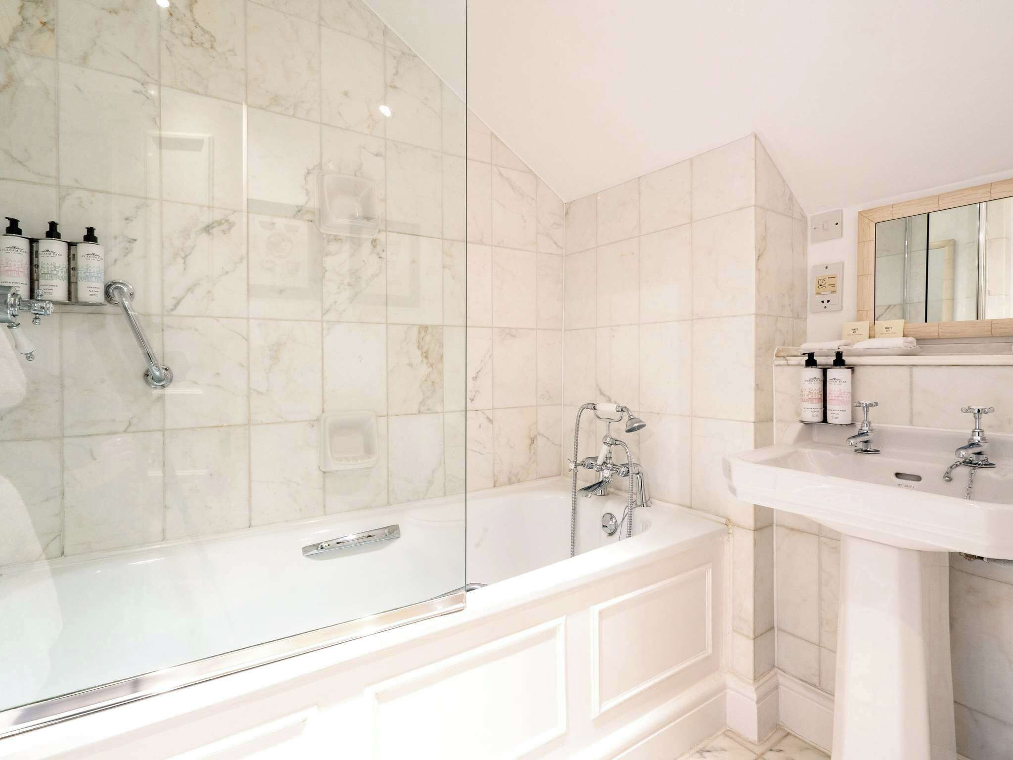 Un baño con ducha de vidrio, una bañera blanca y un tocador con espejo.