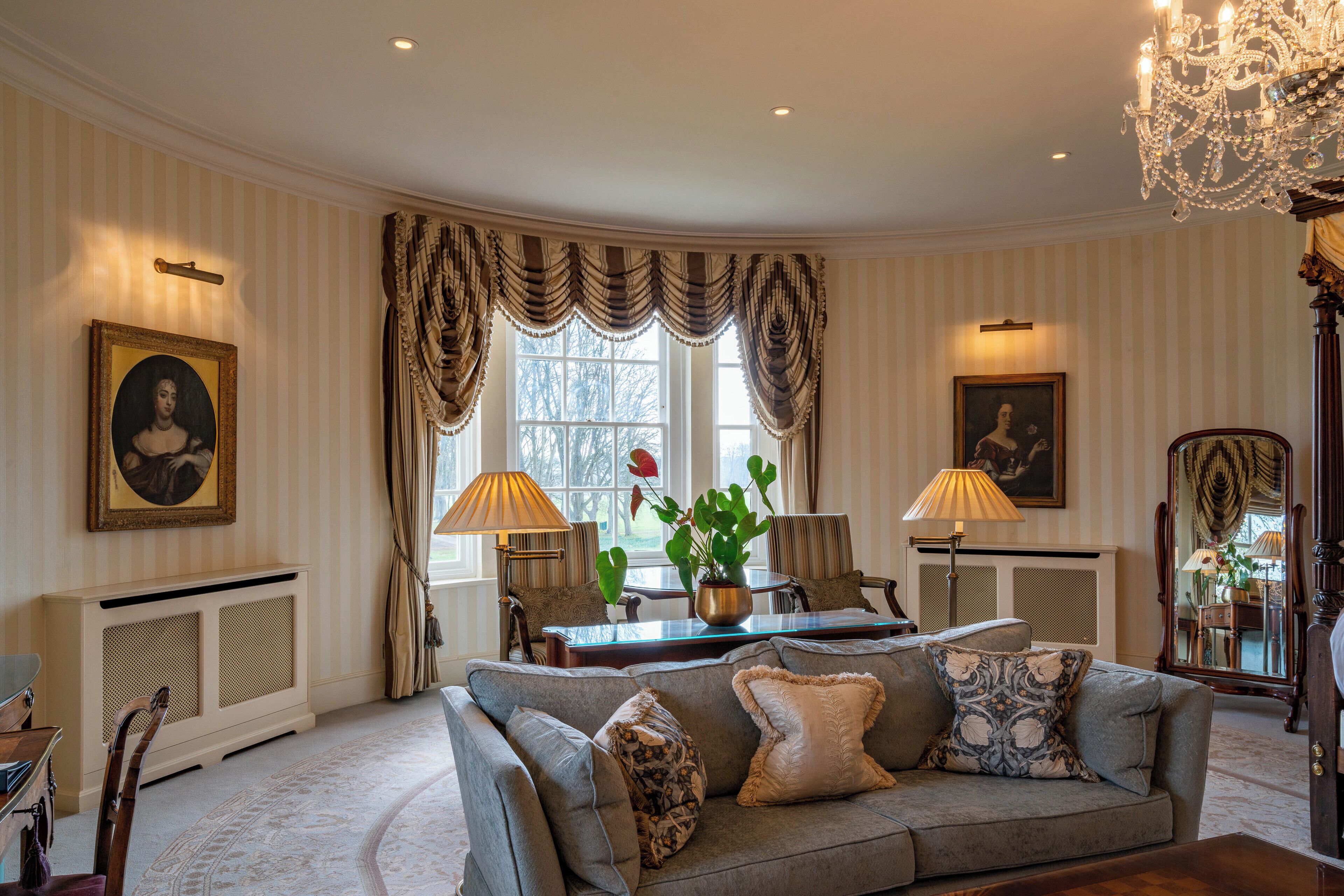 A room with a sofa, two lamps, a table, and a chair.