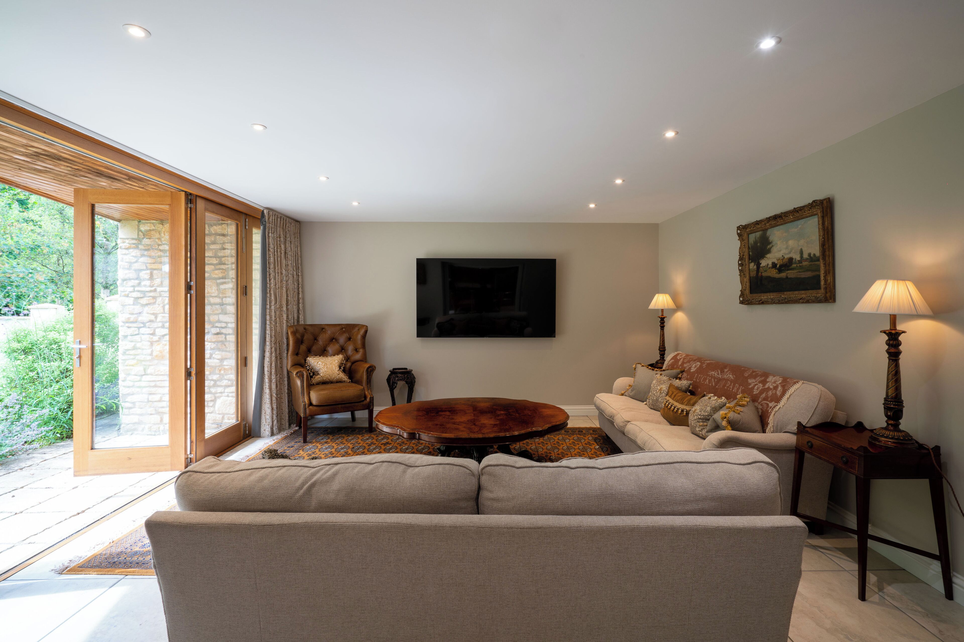A living room with a sofa, armchairs, a coffee table, and a painting on the wall.