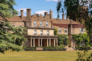 A large, historic building with a symmetrical facade, columns at the entrance, and a well-maintained lawn. - Lucknam Park, Emblems Collection (Chippenham)