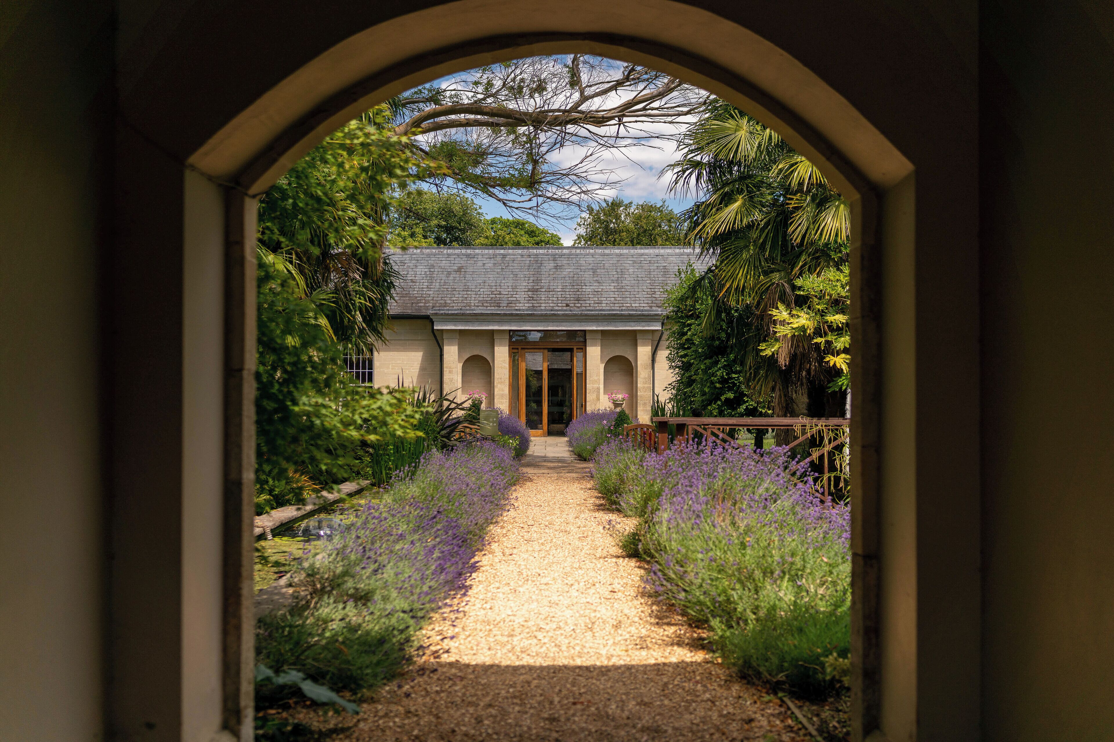 A pathway leading to a building with a grey roof and arched windows.