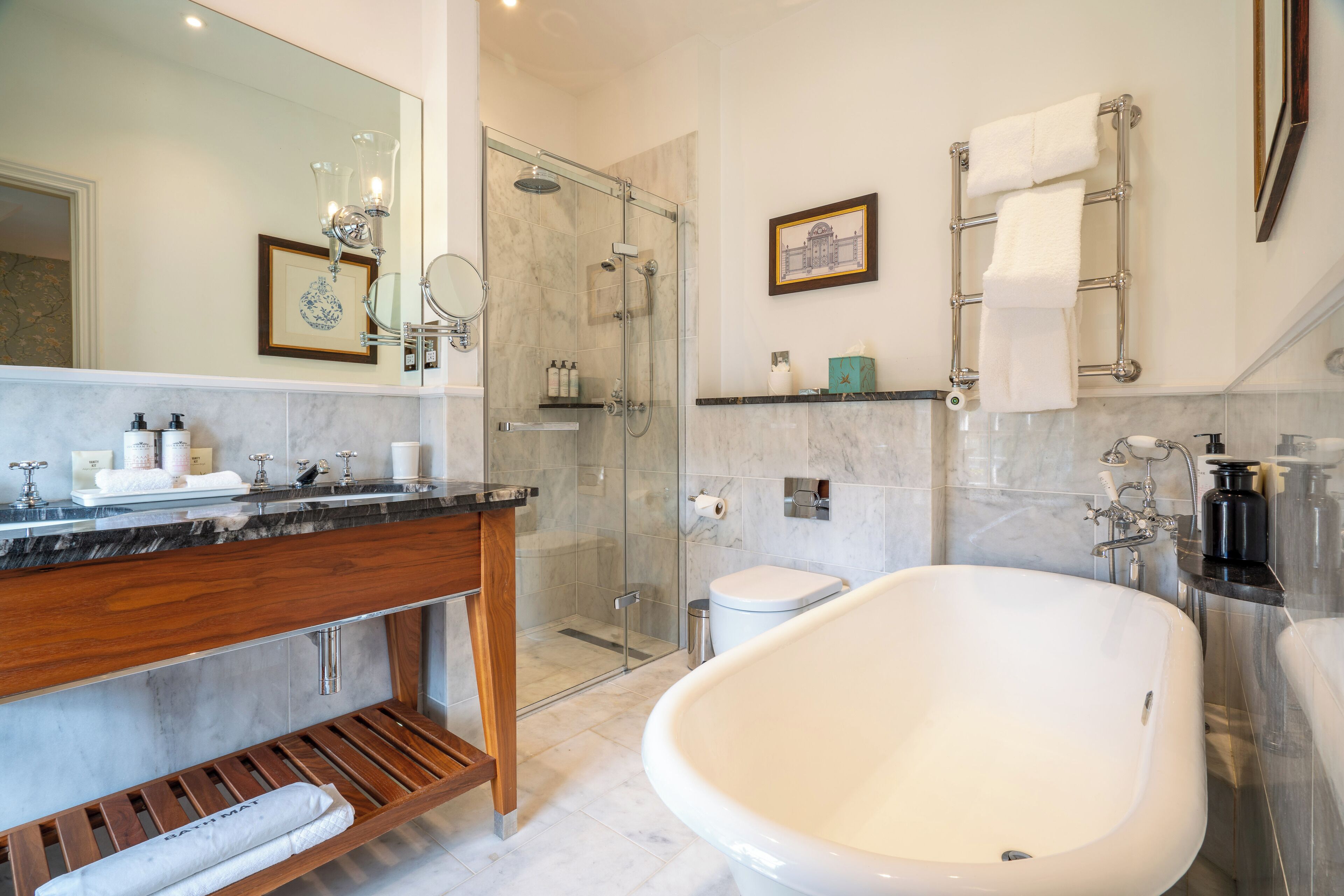 Een moderne badkamer met een vrijstaand bad, een douche met glazen wanden en een wastafel met een marmeren blad.