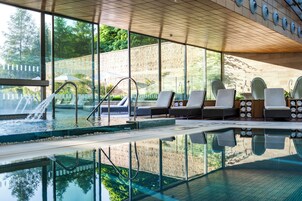 Una piscina techada, una piscina al aire libre, sombrillas