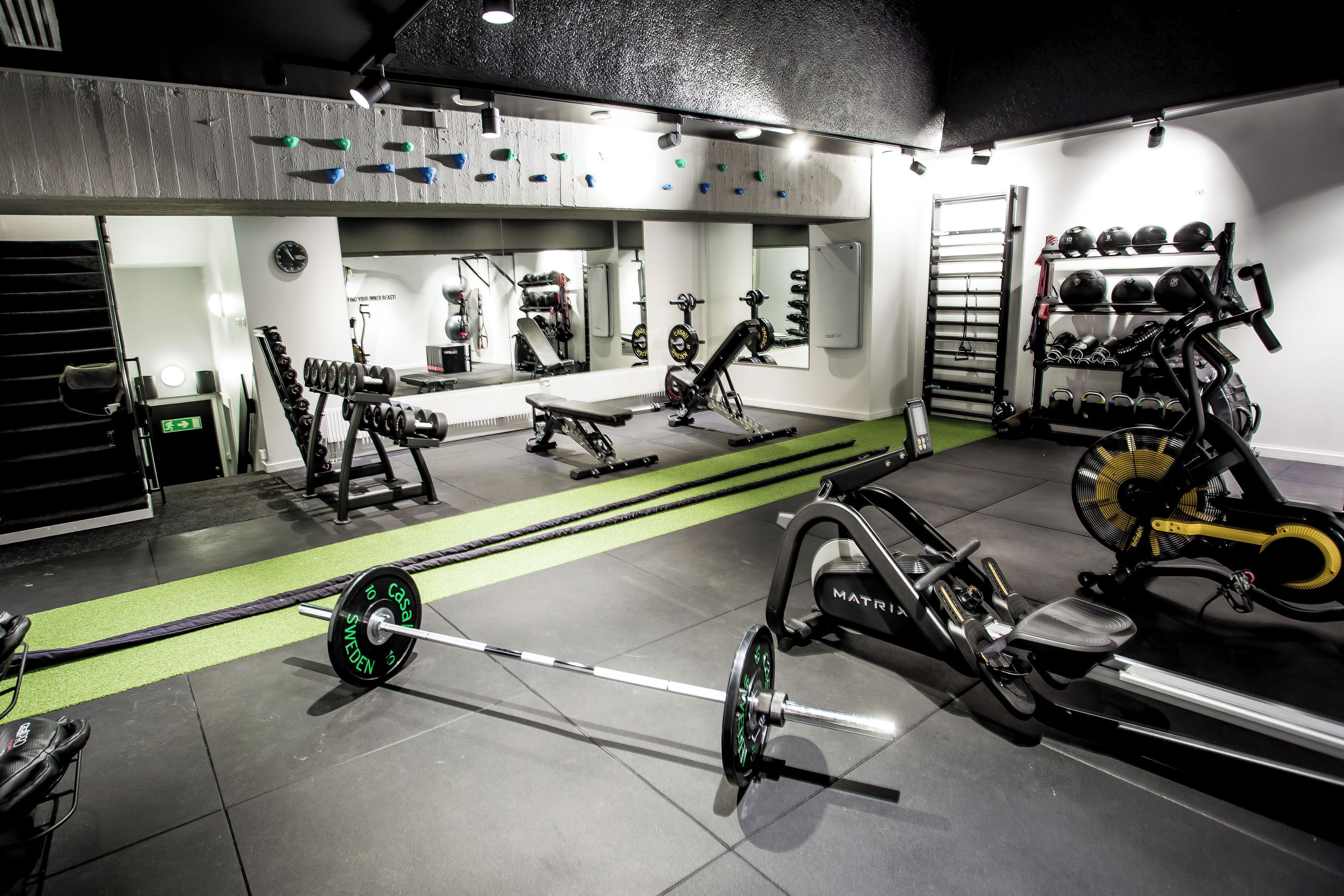 A gym with weightlifting equipment, treadmills, and a mirror wall.