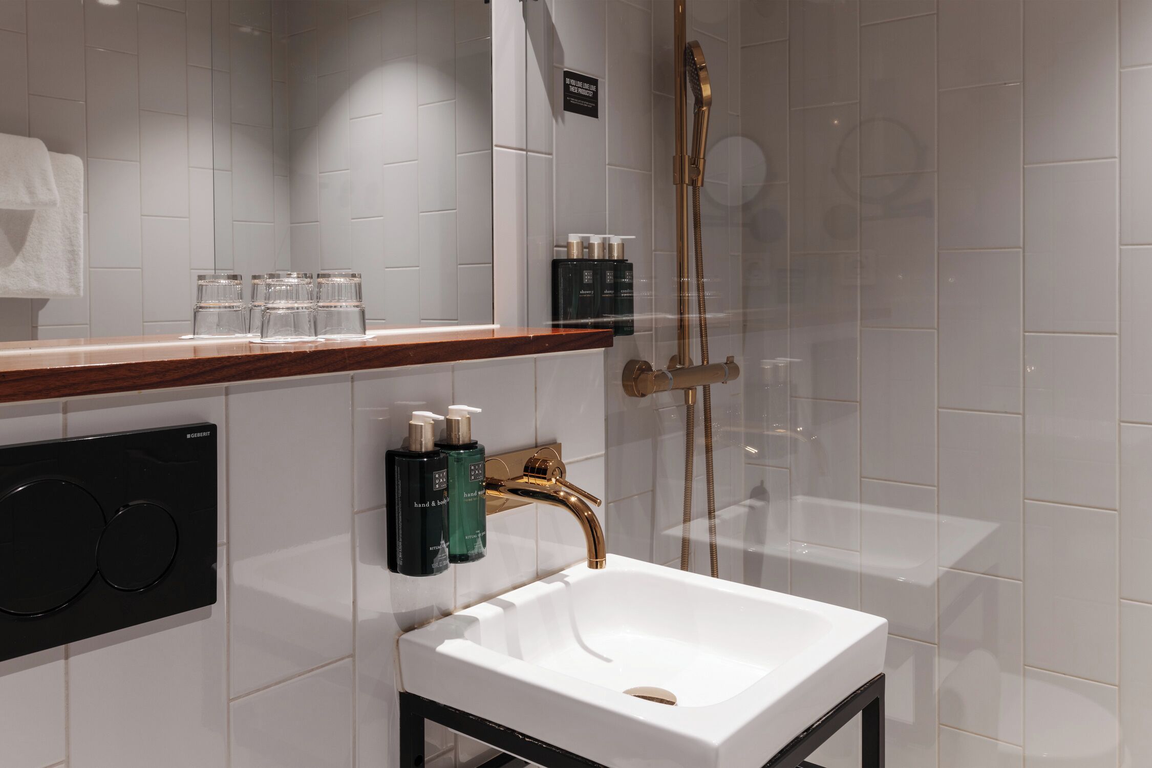 Ein modernes Badezimmer mit einem weißen Waschbecken, einer Holzausziehtafel und einer Duschkabine.
