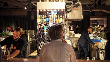 A bar area with a neon sign reading "Cocktails" and a bartender preparing drinks.