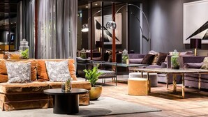 A modern living room with a sofa set, a coffee table, and a dining table. - Clarion Hotel Amaranten (Stockholm)
