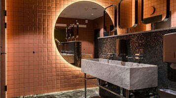 Un baño moderno con un espejo grande, dos lavabos y un muro con azulejos.